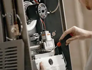 Furnace repair technician inspecting internal components and wiring in Las Vegas, NV