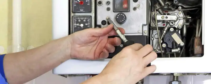 Heating repair technician adjusting boiler controls and components in Las Vegas, NV