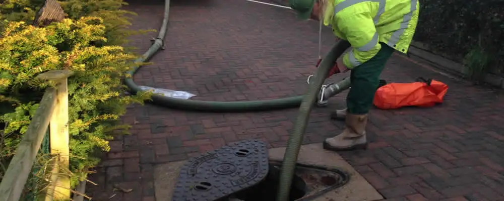 Septic tank cleaning technician servicing a septic tank with a vacuum hose in Las Vegas, NV