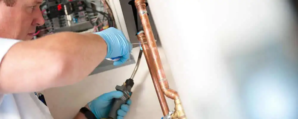 Water heater repair technician testing copper pipe connections and controls in Las Vegas, NV